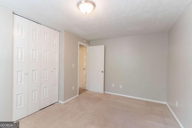unfurnished bedroom featuring a closet, baseboards, carpet flooring, and a textured ceiling