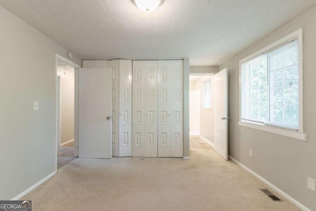 unfurnished bedroom with carpet floors, a closet, a textured ceiling, and visible vents