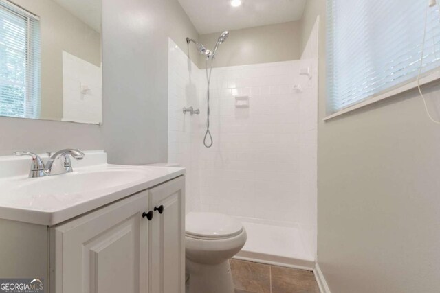 full bath with vanity, tile patterned floors, toilet, and tiled shower