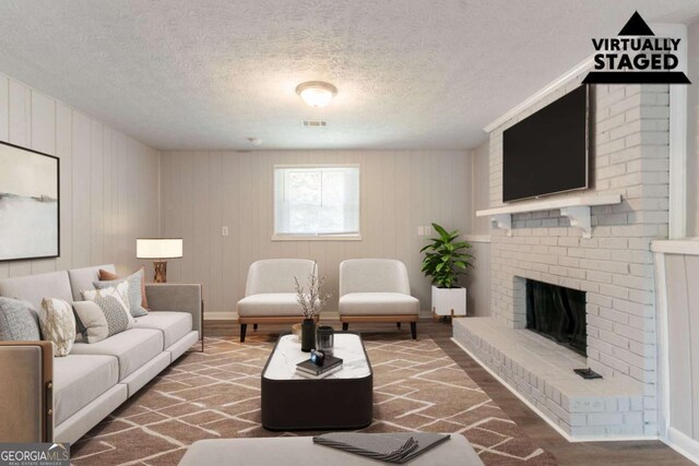 living area featuring visible vents, a textured ceiling, wood finished floors, and a fireplace
