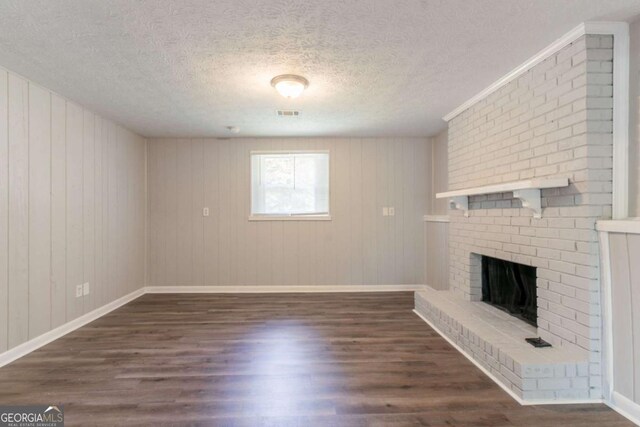unfurnished living room featuring visible vents, a fireplace, baseboards, dark wood-style floors, and a textured ceiling