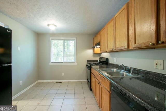 kitchen featuring brown cabinetry, dark countertops, a sink, baseboards, and black appliances
