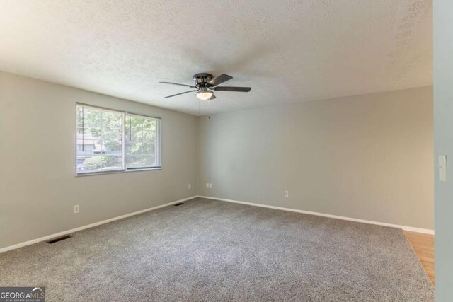 empty room with baseboards, ceiling fan, a textured ceiling, and carpet floors