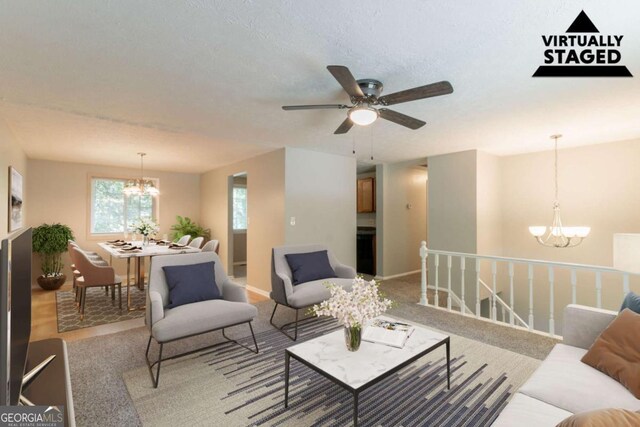 carpeted living room with baseboards and ceiling fan with notable chandelier