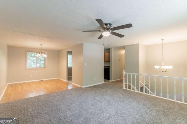 spare room with baseboards, light colored carpet, and ceiling fan with notable chandelier