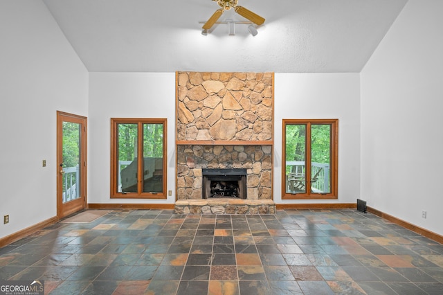 unfurnished living room featuring baseboards, healthy amount of natural light, stone tile floors, and lofted ceiling