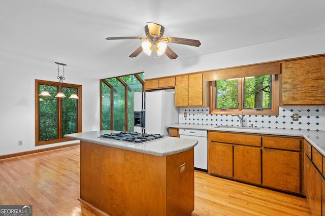 kitchen featuring white appliances, a sink, tasteful backsplash, a ceiling fan, and plenty of natural light