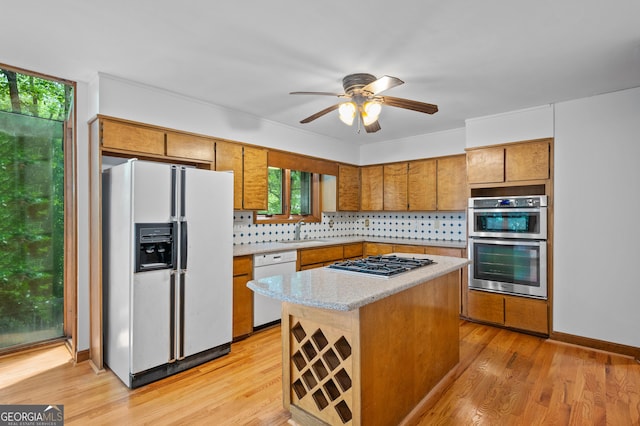 kitchen featuring appliances with stainless steel finishes, brown cabinetry, tasteful backsplash, and a sink