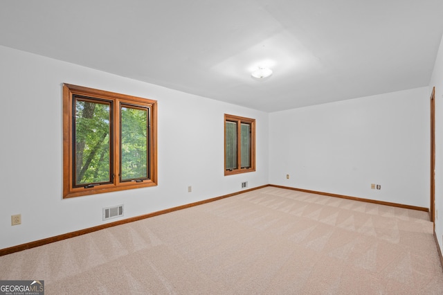 spare room with light colored carpet, visible vents, and baseboards