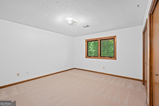 unfurnished bedroom featuring light carpet, baseboards, a textured ceiling, and a closet