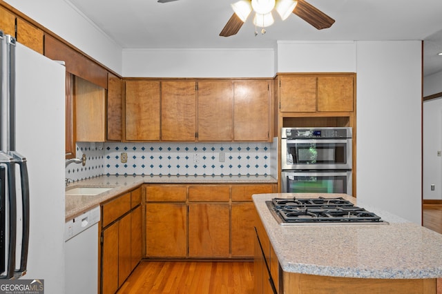 kitchen with a sink, ceiling fan, light countertops, and appliances with stainless steel finishes