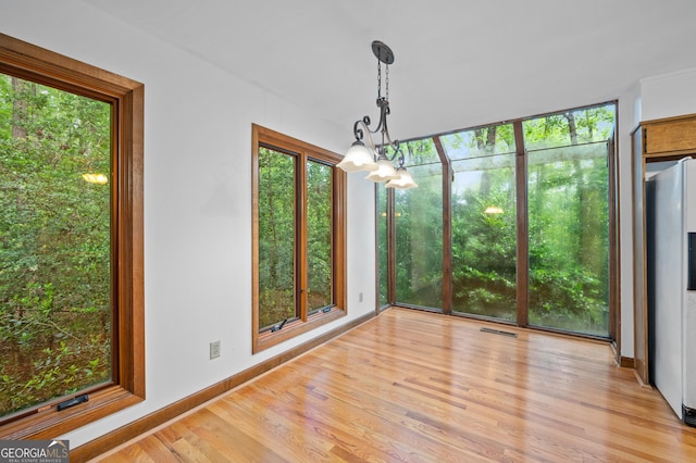unfurnished dining area with light wood finished floors, visible vents, baseboards, and a chandelier