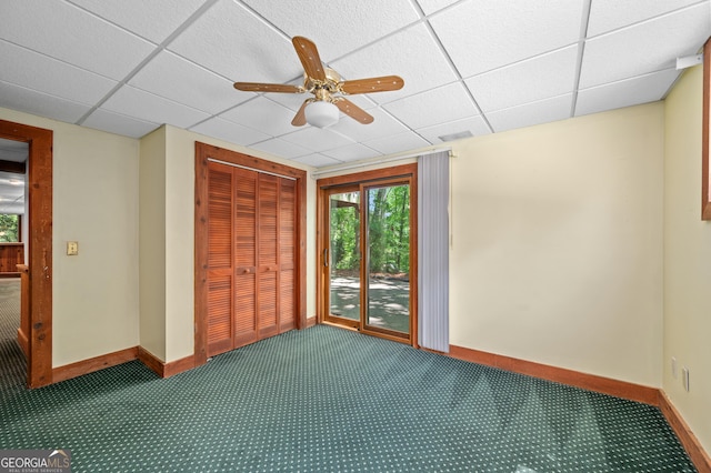 carpeted empty room featuring a paneled ceiling, ceiling fan, baseboards, and visible vents