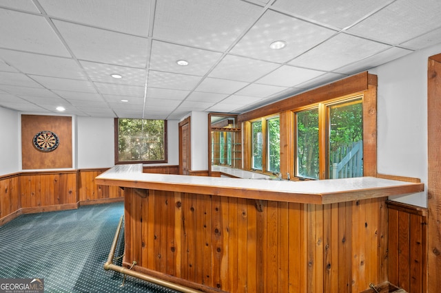 bar featuring bar, carpet flooring, wooden walls, and wainscoting