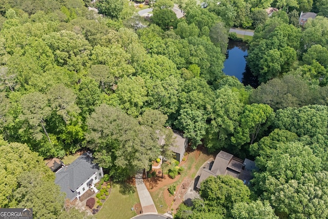 view of property location with a nearby body of water and a forest