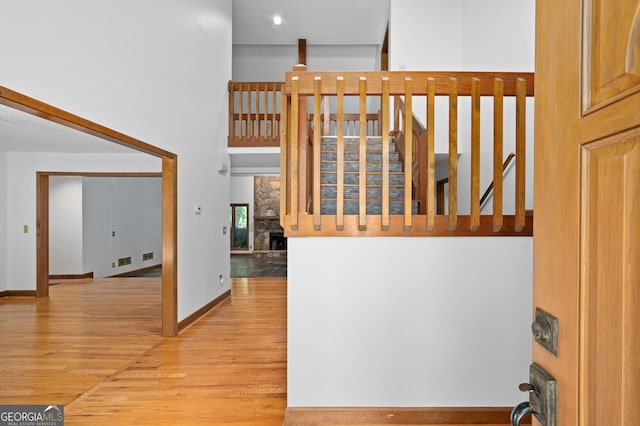 stairs with baseboards, a stone fireplace, visible vents, and wood finished floors