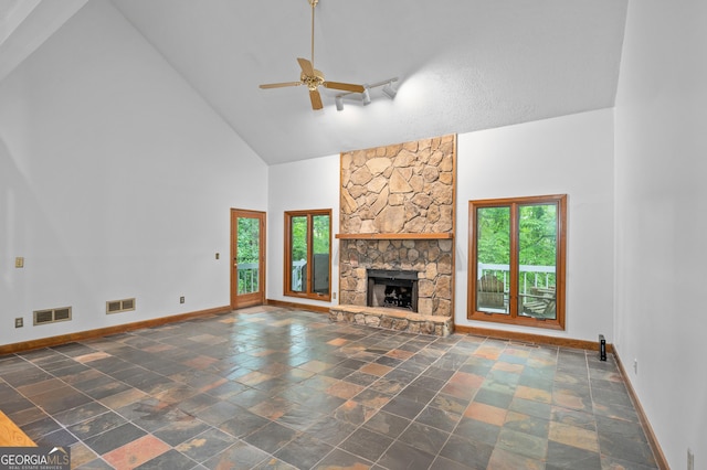 unfurnished living room featuring high vaulted ceiling, healthy amount of natural light, baseboards, ceiling fan, and stone tile floors