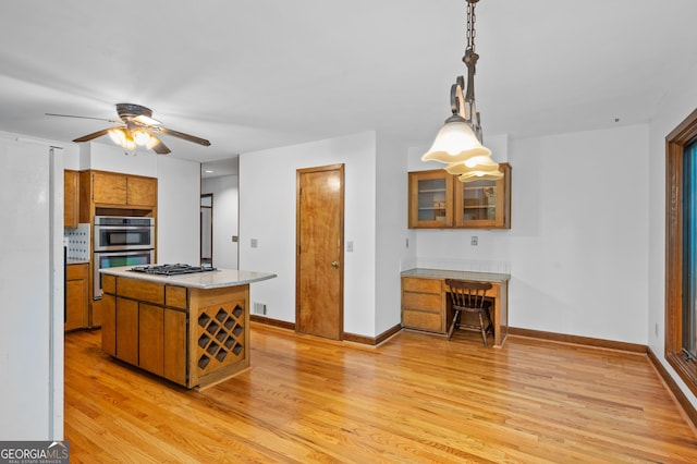 kitchen featuring brown cabinetry, appliances with stainless steel finishes, light wood finished floors, ceiling fan, and light countertops