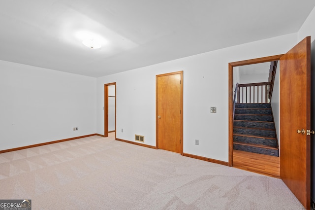 unfurnished room featuring light colored carpet, baseboards, and stairway