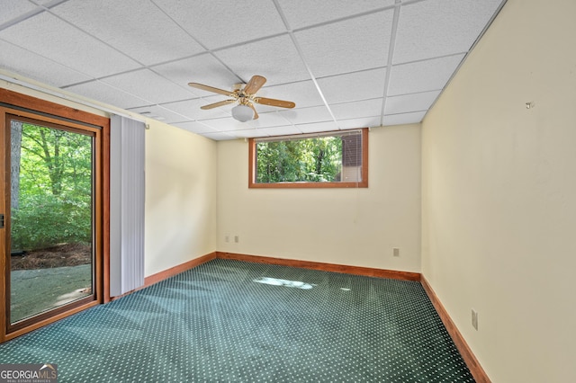 carpeted empty room with baseboards, a ceiling fan, and a paneled ceiling