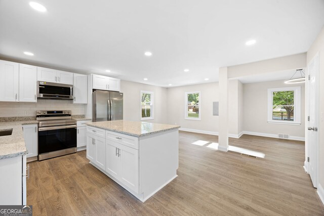 kitchen with decorative backsplash, light wood-style flooring, appliances with stainless steel finishes, and white cabinetry