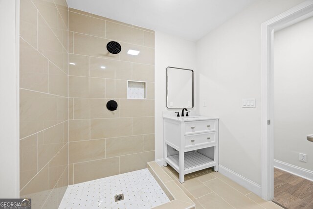 full bathroom with vanity, baseboards, and tiled shower