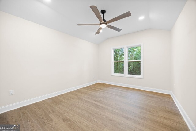 spare room featuring baseboards, ceiling fan, wood finished floors, and lofted ceiling