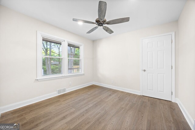unfurnished room with baseboards, ceiling fan, visible vents, and wood finished floors