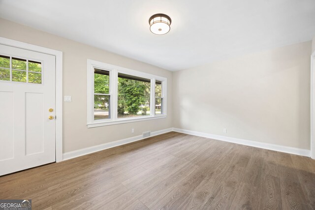 foyer with baseboards, visible vents, plenty of natural light, and wood finished floors