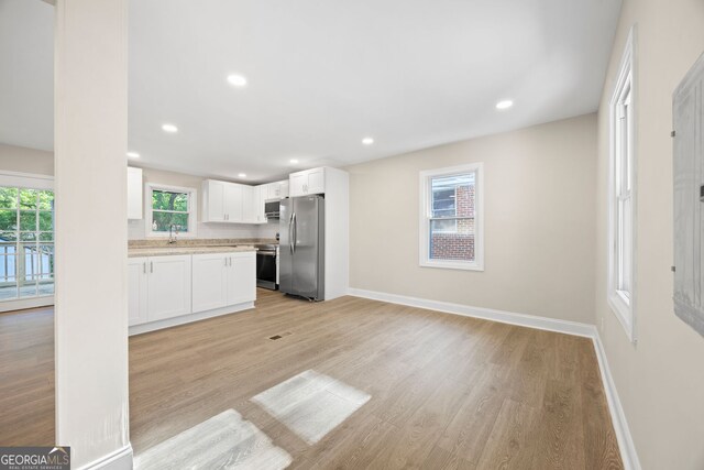 kitchen with baseboards, light wood-type flooring, recessed lighting, white cabinetry, and stainless steel appliances