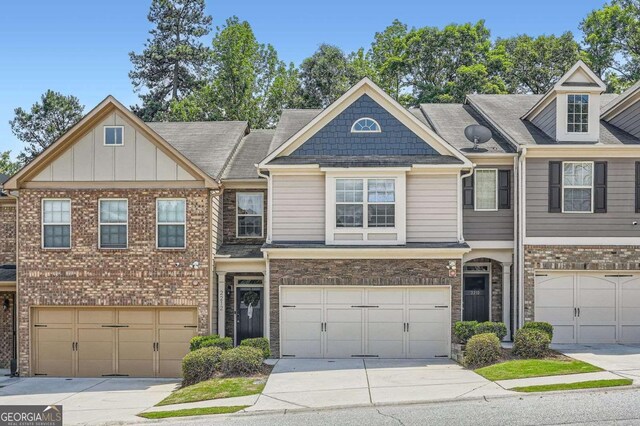 view of property with an attached garage, roof with shingles, driveway, and brick siding