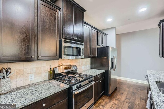 kitchen with dark brown cabinetry, baseboards, dark wood-style floors, light stone counters, and stainless steel appliances