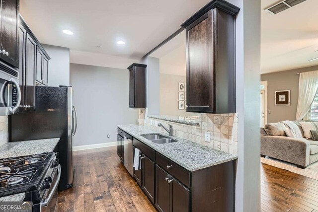 kitchen with a sink, dark brown cabinetry, dark wood finished floors, and visible vents