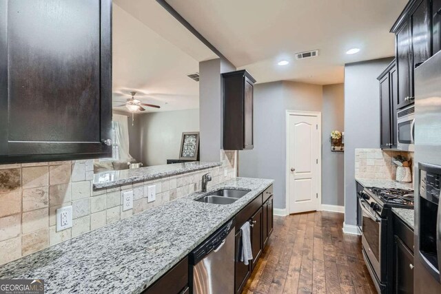 kitchen with stainless steel appliances, baseboards, decorative backsplash, and a sink
