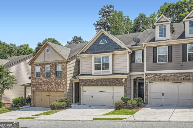 multi unit property with a garage, driveway, and stone siding