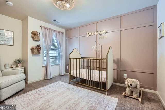 bedroom with a crib, baseboards, carpet flooring, and visible vents
