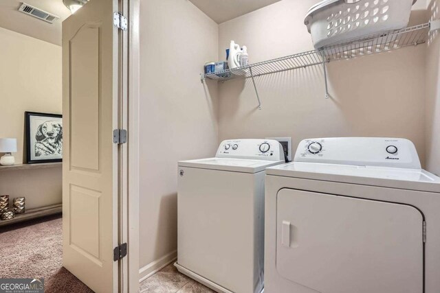 laundry area featuring laundry area, visible vents, washing machine and clothes dryer, baseboards, and light carpet