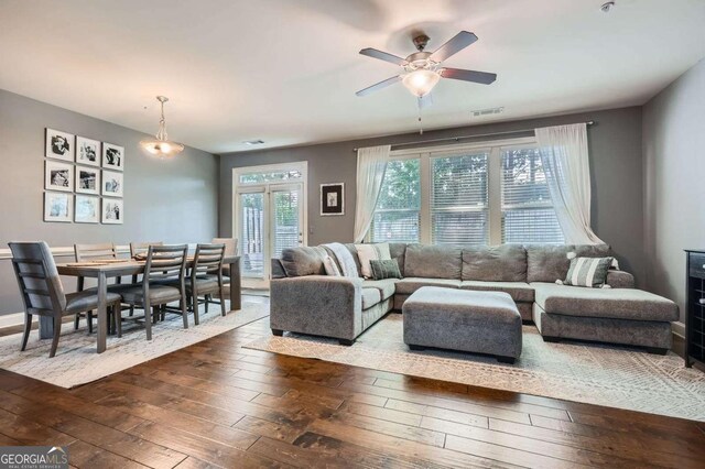 living room featuring visible vents, a ceiling fan, and dark wood-style flooring