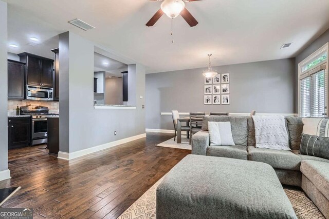 living area with baseboards, ceiling fan, dark wood-style flooring, and visible vents