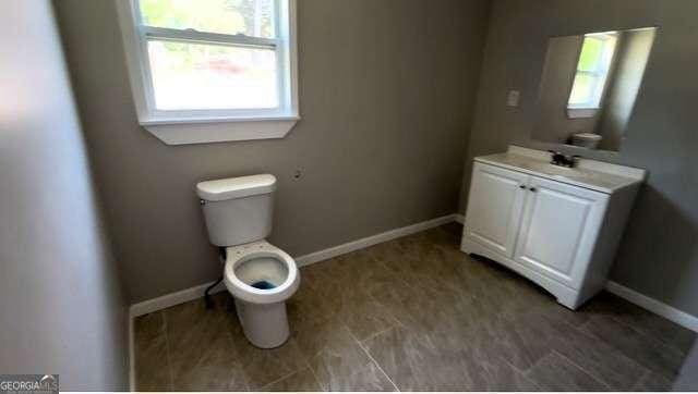 50 Ivy St, Porterdale, GA 30014 - half bathroom with toilet, baseboards, a wealth of natural light, and vanity