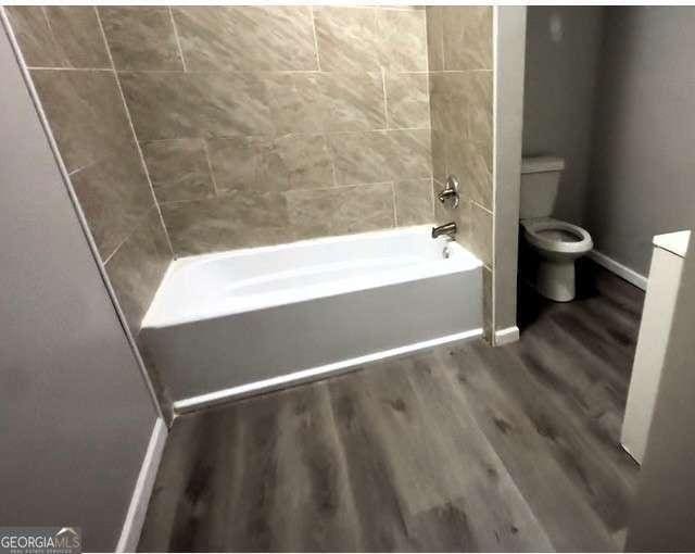 50 Ivy St, Porterdale, GA 30014 - full bathroom with baseboards, toilet, wood finished floors, and tub / shower combination