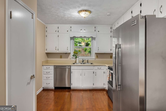 kitchen featuring a sink, a textured ceiling, stainless steel appliances, white cabinetry, and dark wood-style floors