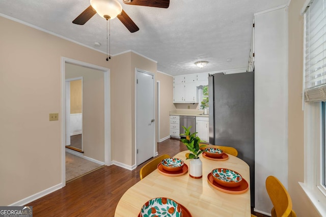 dining room with crown molding, ceiling fan, a textured ceiling, dark wood finished floors, and baseboards