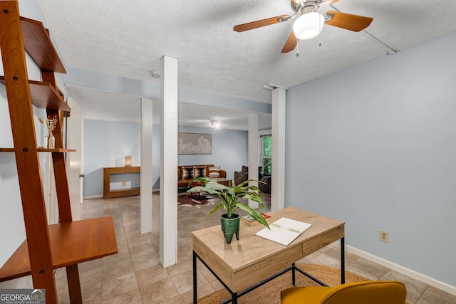 office featuring baseboards, light tile patterned floors, a textured ceiling, and ceiling fan