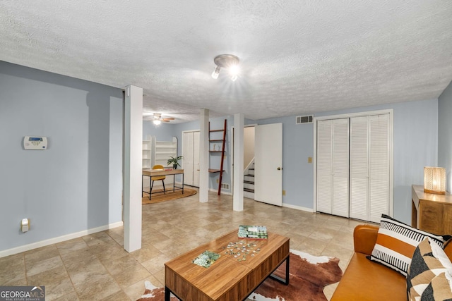 living room with baseboards, a textured ceiling, stairs, and visible vents