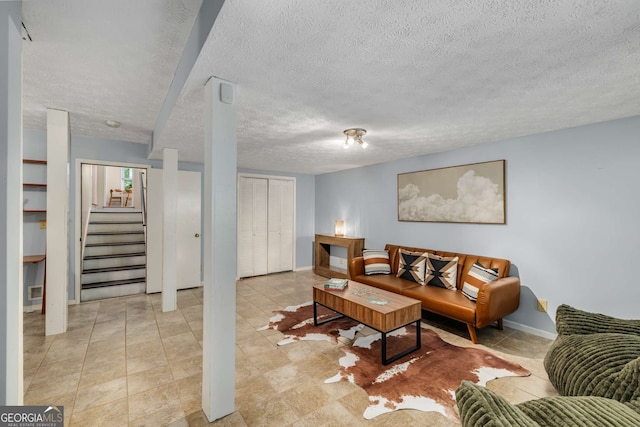 living area with baseboards, a textured ceiling, and stairway