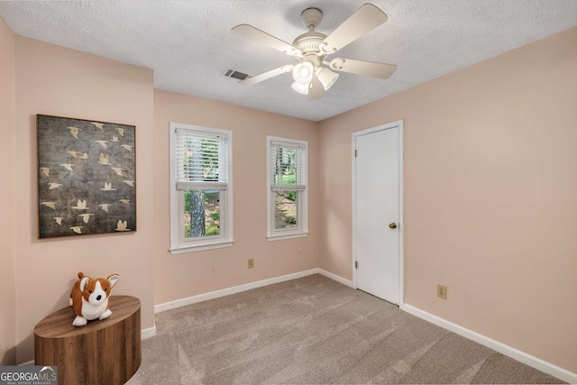 empty room with baseboards, carpet flooring, a textured ceiling, and visible vents