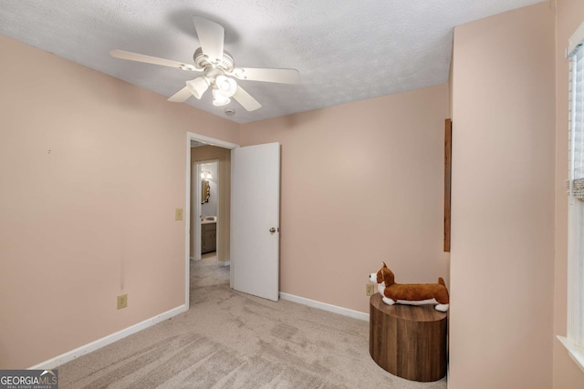 empty room featuring carpet floors, a ceiling fan, baseboards, and a textured ceiling