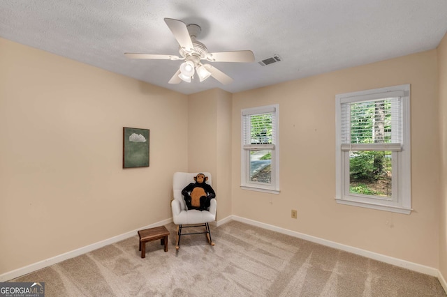 living area featuring baseboards, plenty of natural light, a ceiling fan, and carpet flooring