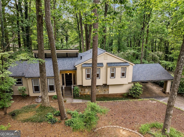 split level home featuring roof with shingles, an attached carport, and driveway
